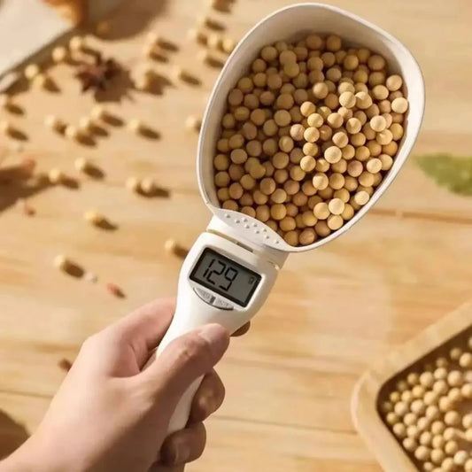 Digital pet food measuring spoon with LED display showing weight in grams, filled with pet food.